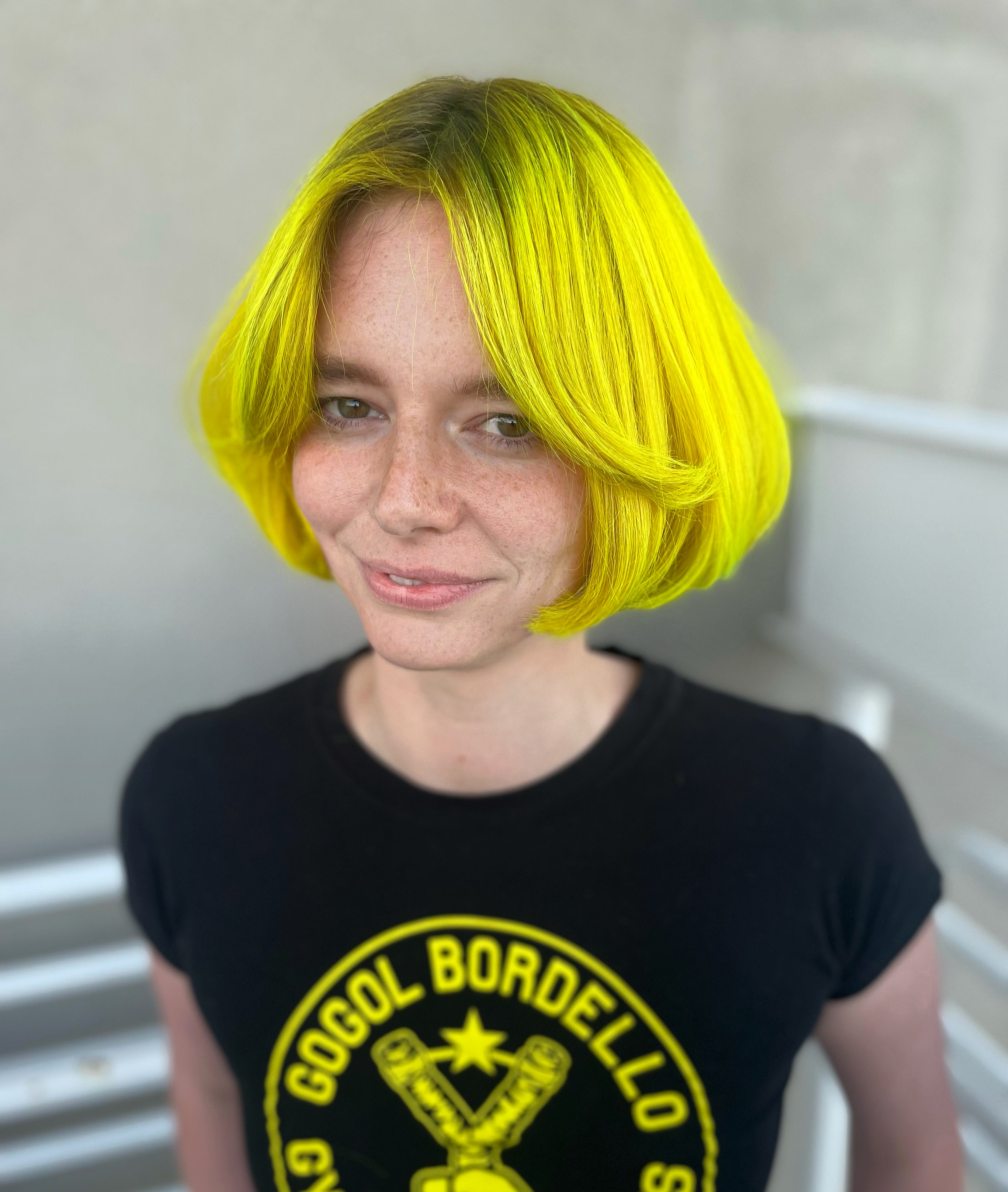 A smiling client with a medium length yellow haircut.