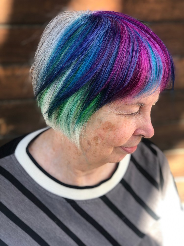 A client with a bob cut streaked with magenta, purple, blue, and turquoise