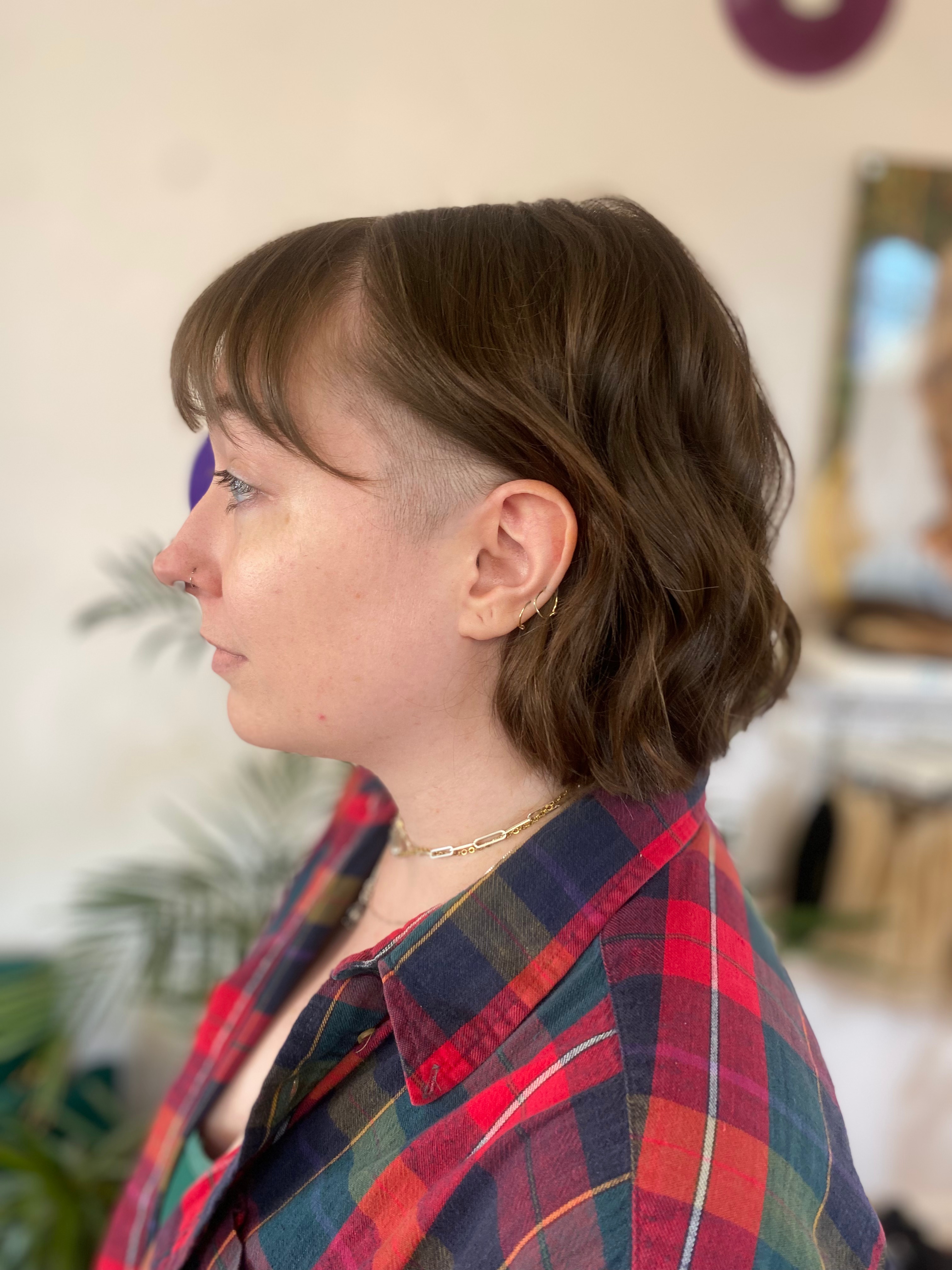 A client with a sharply designed cut on her short, wavy hair.