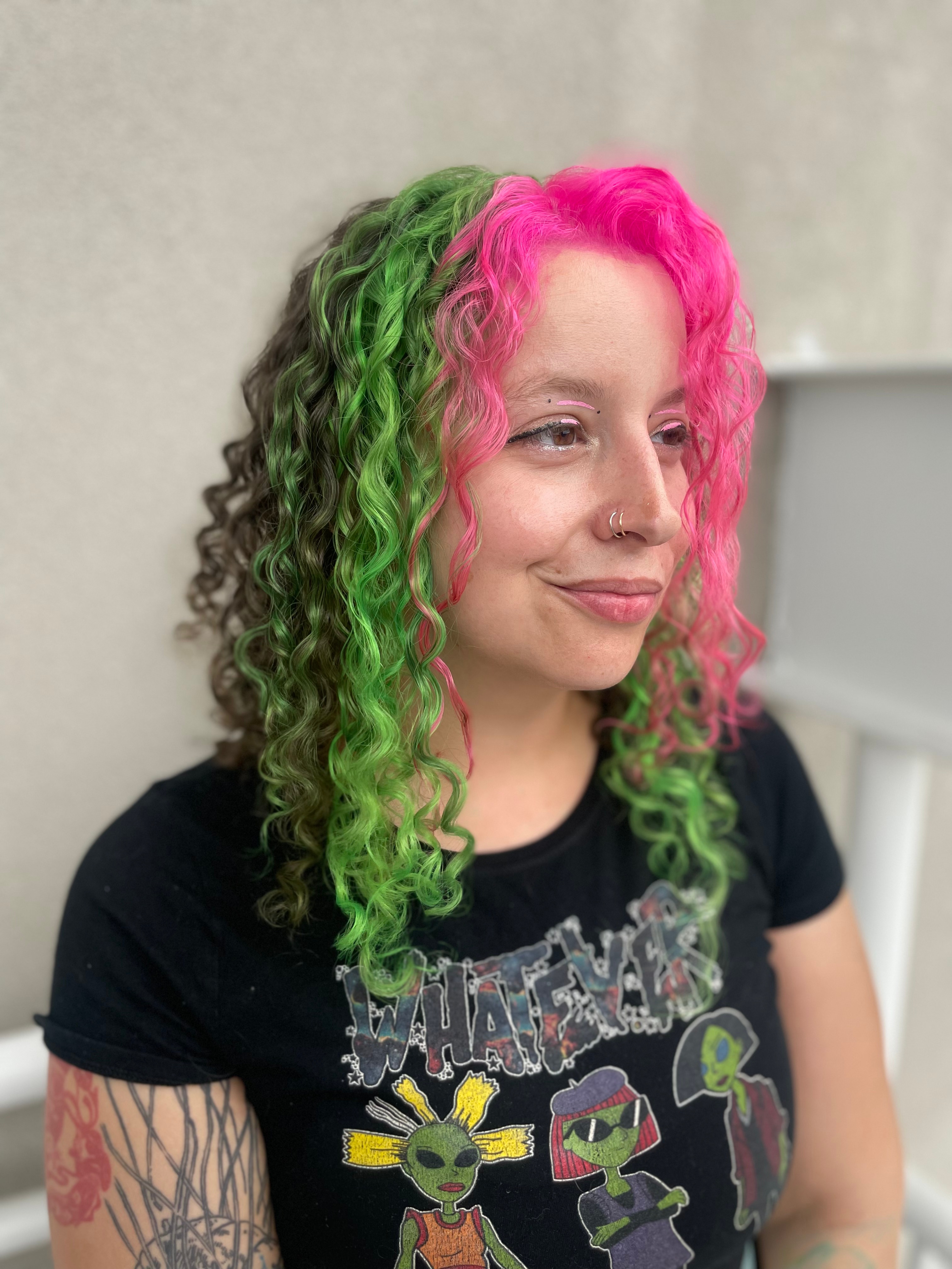 A client with wavy hair streaked in green and pink.