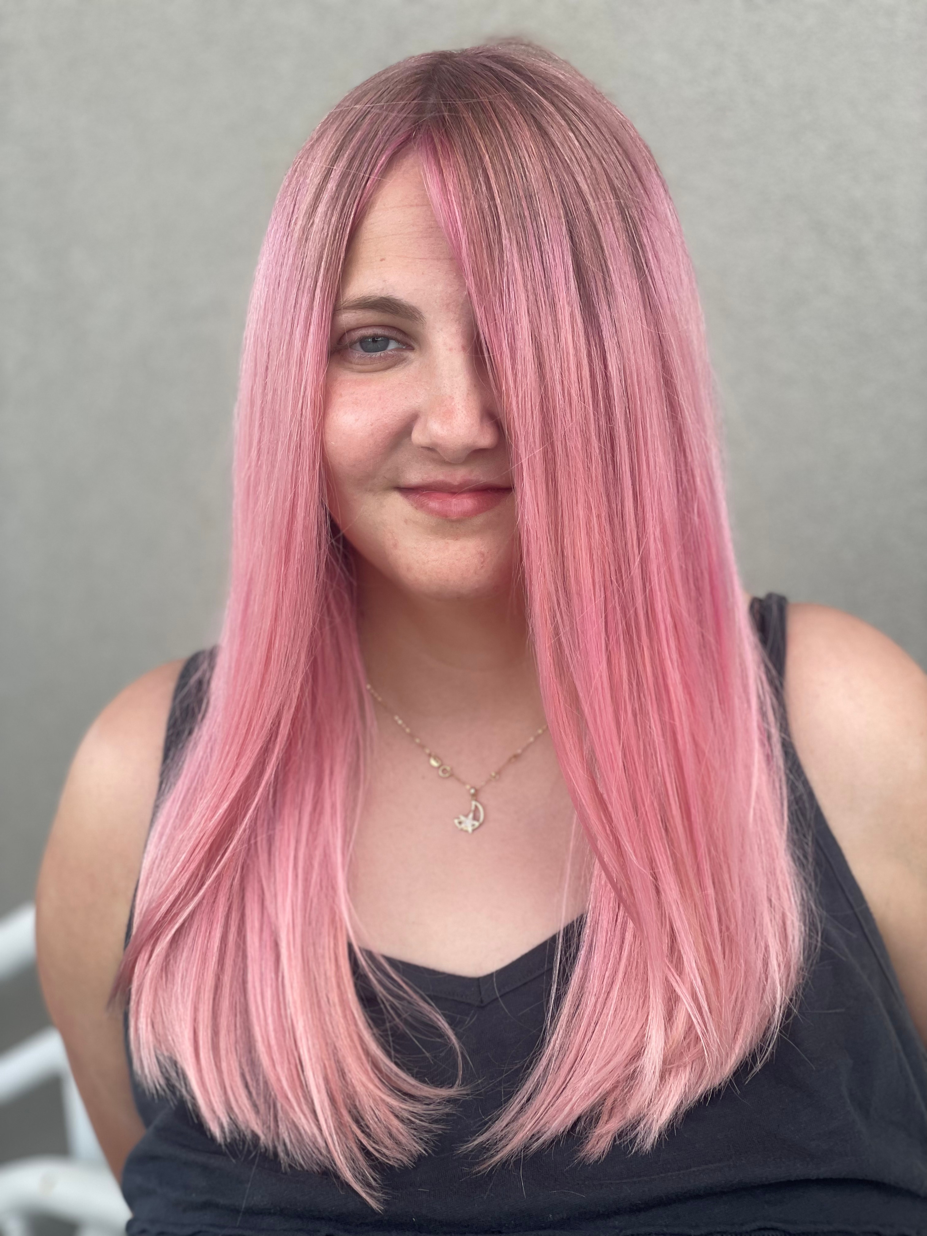 A smiling client with long pink hair