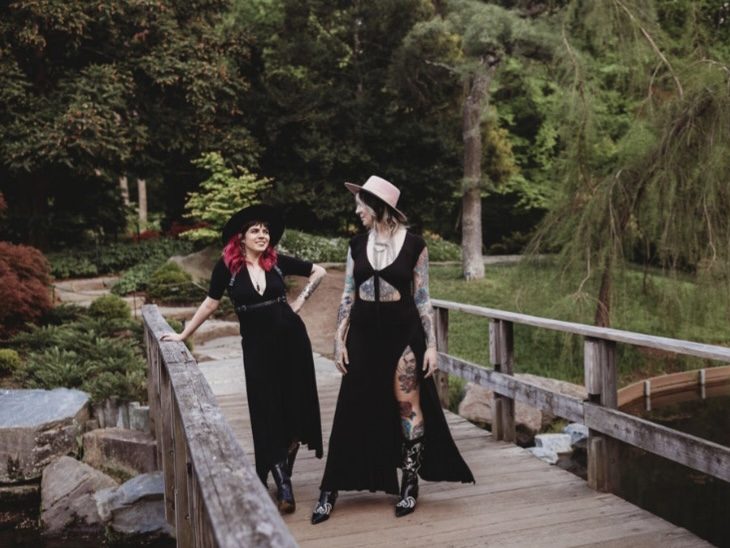 Hair stylists Chelsea (left) and Sara (right) cross a bridge in a park.