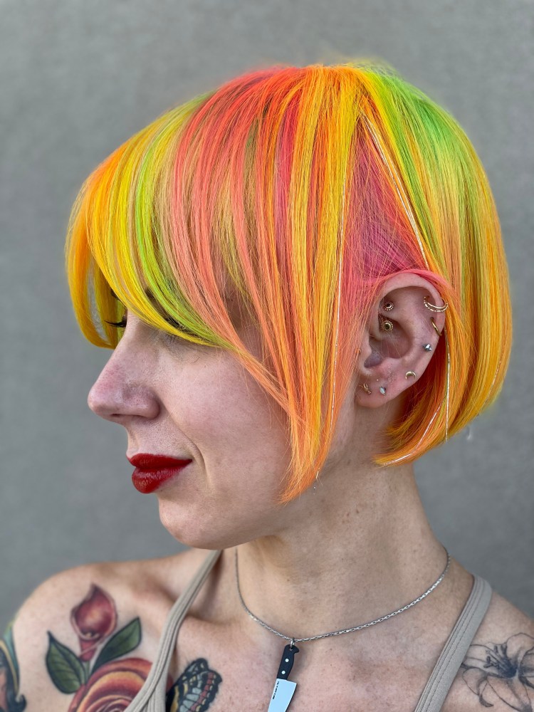 A client with a bob cut streaked with neon green, pink, orange, and yellow